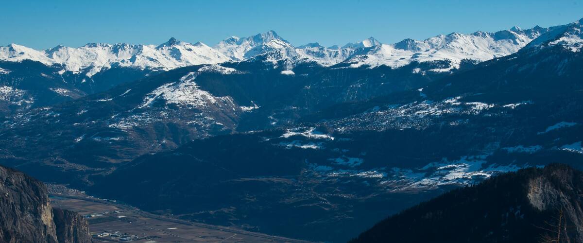 A mountain range with snow-capped peaks and a valley below.