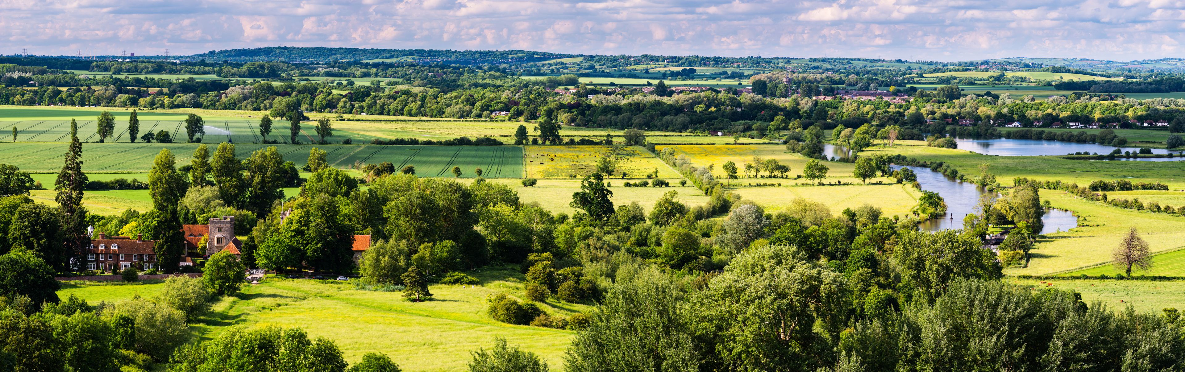 A rural landscape with fields, a river, and a manor house.
