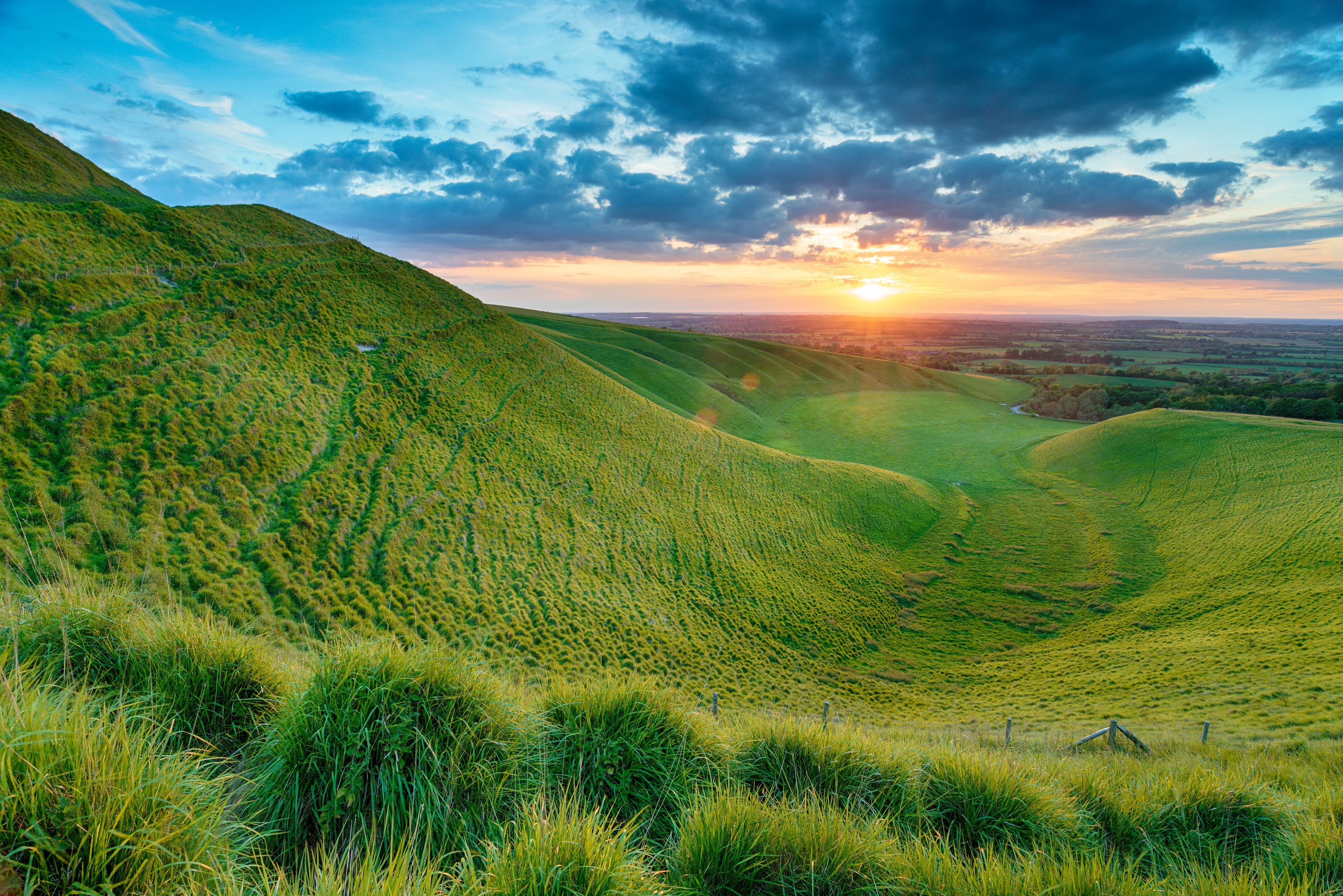 Rolling green hills with a sunset in the background.