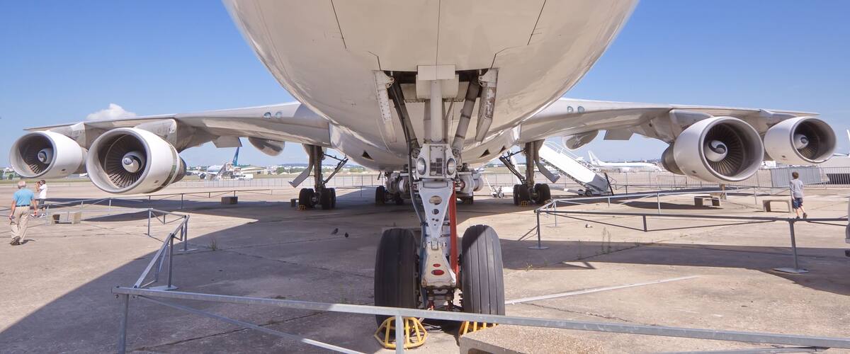 The underside of a large commercial airplane with four engines, landing gear, and a support structure.