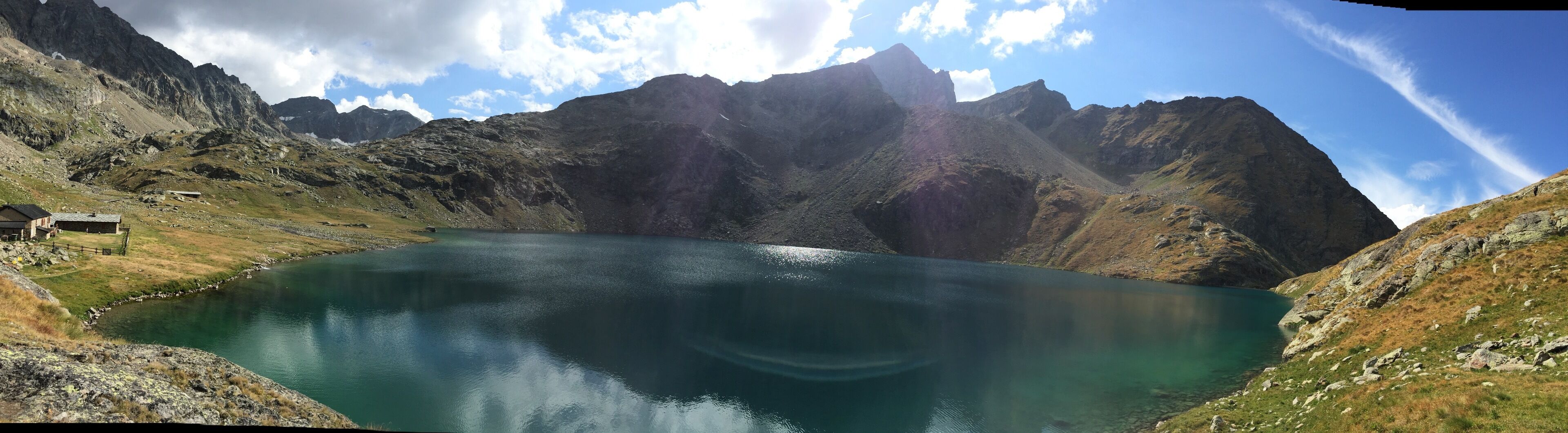 A mountain lake surrounded by rugged terrain and a small building near the water's edge.