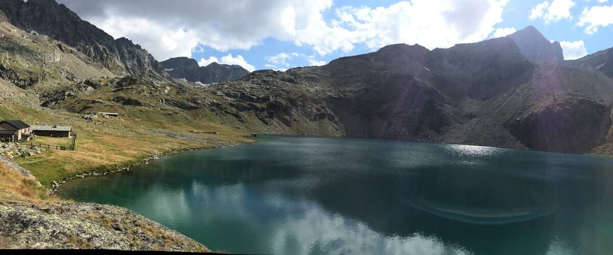 A mountain lake surrounded by rugged terrain and a small building near the water's edge.