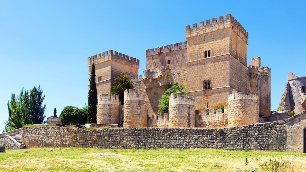 A historic stone castle with multiple towers and a surrounding stone wall.