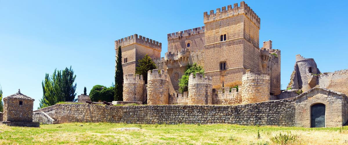 A historic stone castle with multiple towers and a surrounding stone wall.