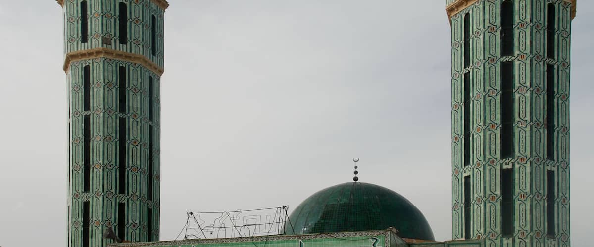 Eine Moschee mit zwei hohen Minaretten und einer großen, grünen Kuppel.