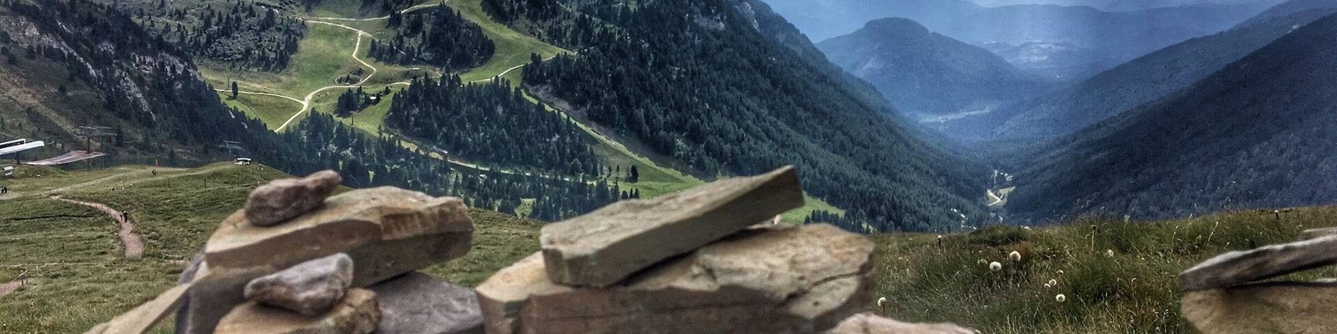 A mountainous landscape with a winding road, stone walls, and a valley.