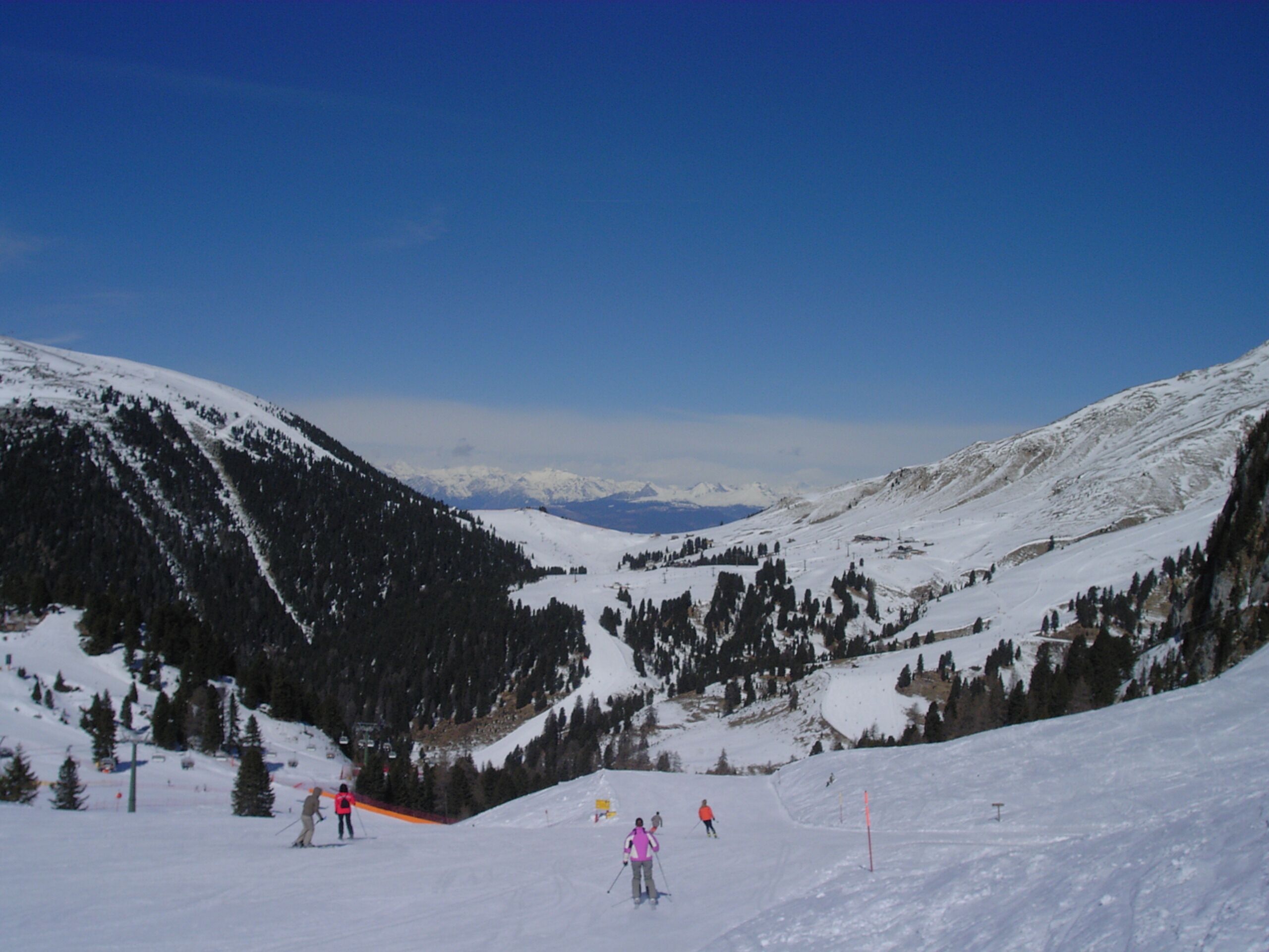 A snow-covered mountain landscape with skiers and a ski lift.