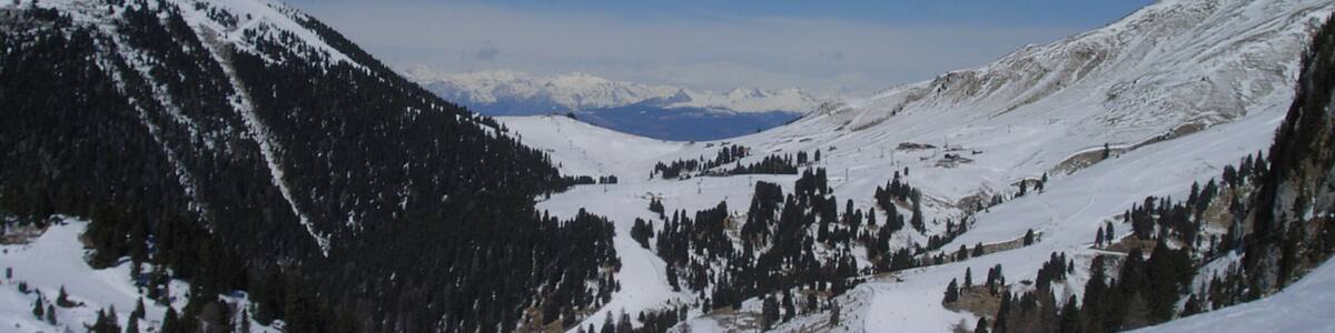 A snow-covered mountain landscape with skiers and a ski lift.