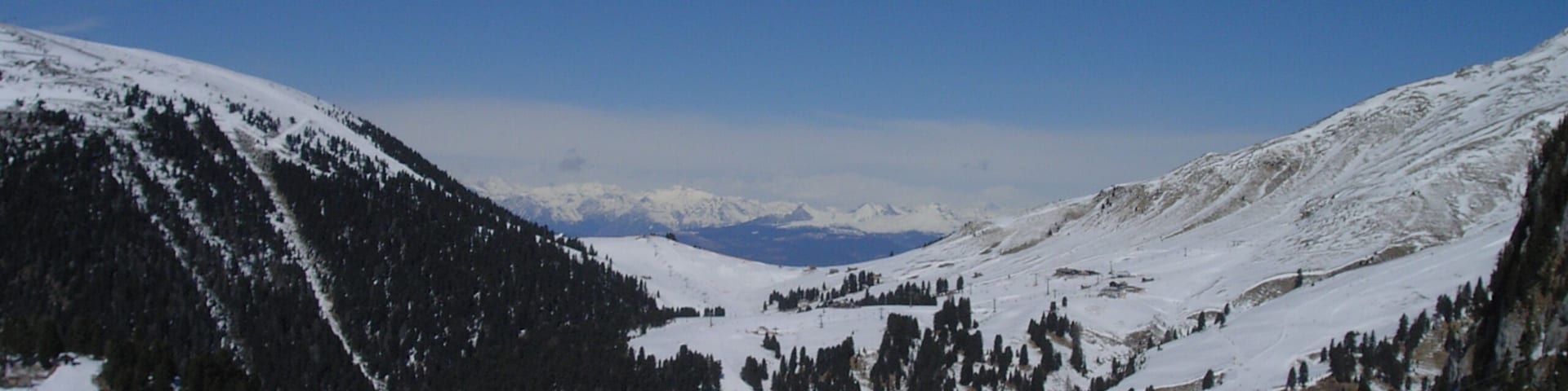 Paisaje montañoso cubierto de nieve con esquiadores y un telesilla.