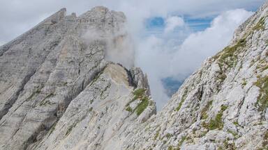 A rugged mountain peak with steep, rocky slopes and patches of greenery.