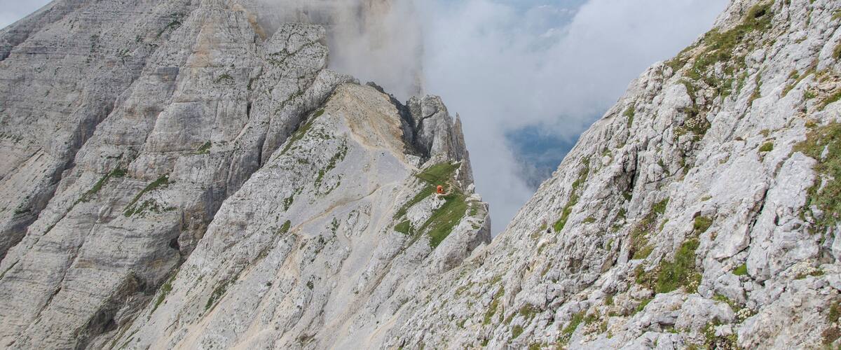 A rugged mountain peak with steep, rocky slopes and patches of greenery.