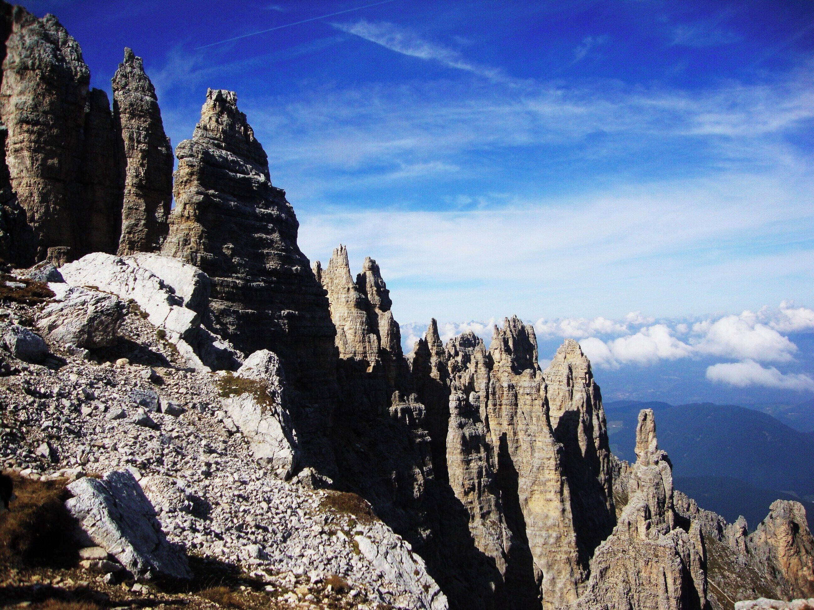 A rugged mountain landscape with sharp, jagged peaks and a clear blue sky.
