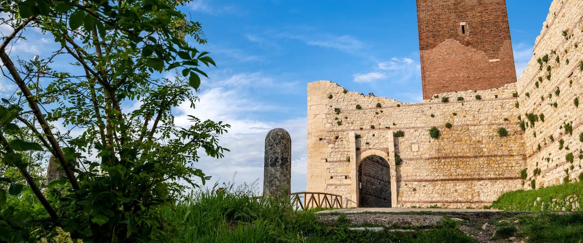 Stone entrance with the tower of Romeo and Juliet's castle in the province of Vicenza in Montecchio Maggiore.Blue sky clouds at Romeo's Bellaguardia Castle Vicenza Veneto Italy Europe.