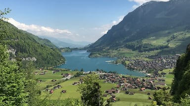 Un valle con un lago rodeado de montañas y un pequeño pueblo.