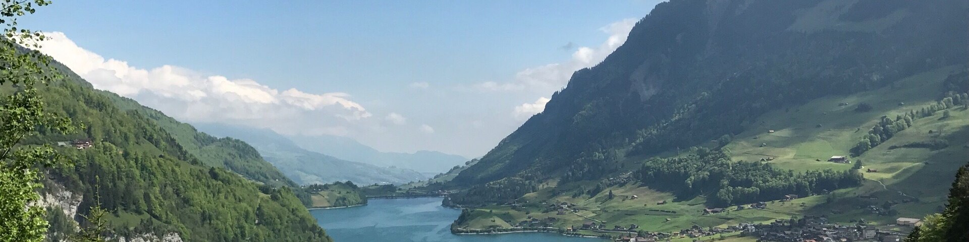 Un valle con un lago rodeado de montañas y un pequeño pueblo.