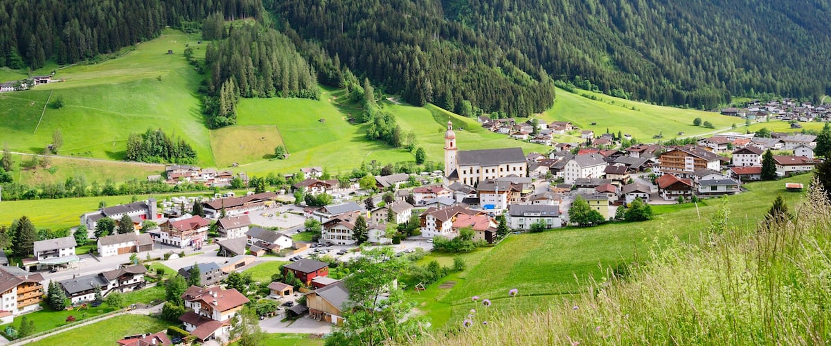 A town nestled in a valley with a prominent church and mountains in the background.