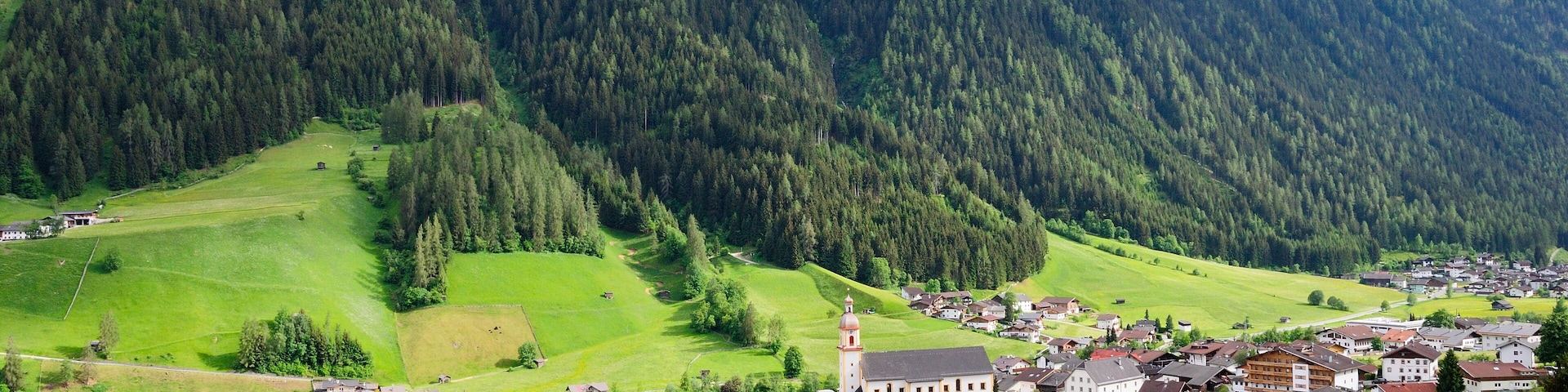 A town nestled in a valley with a prominent church and mountains in the background.