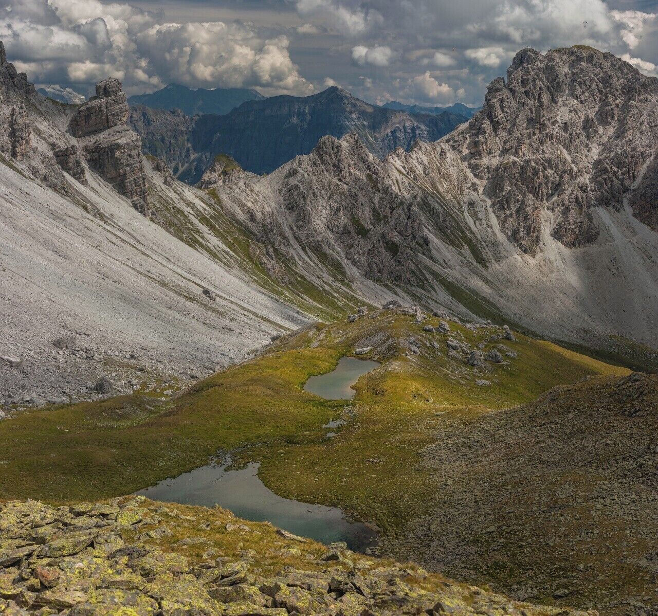 A mountainous landscape with rocky terrain and a small pond.