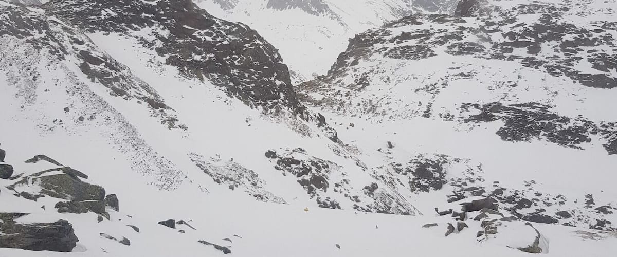 A snow-covered mountain range with rocky outcrops and a valley.