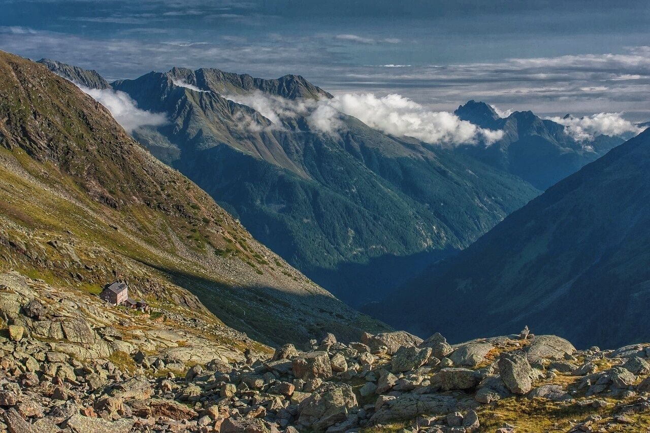 A mountainous landscape with rocky terrain and a small house on a slope.