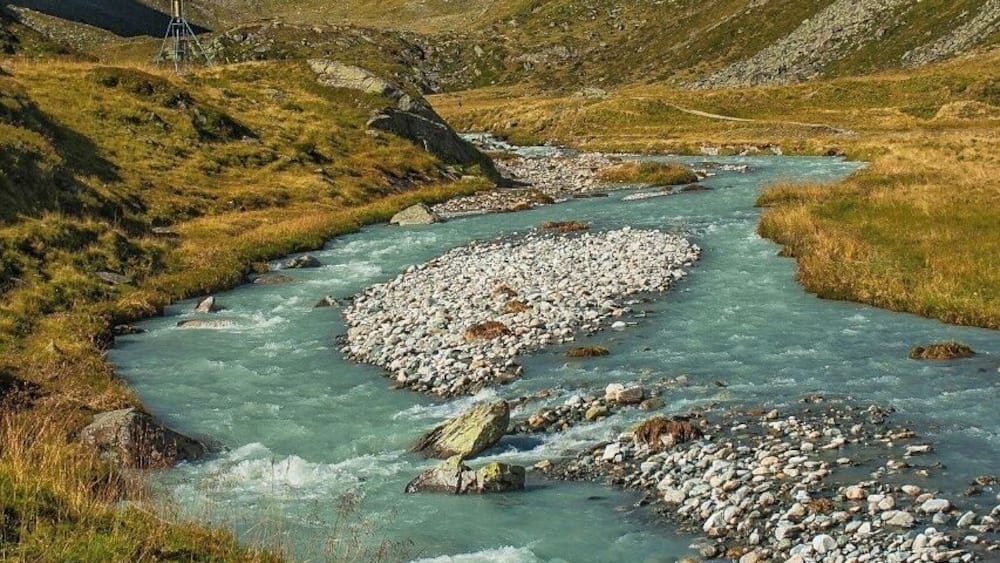 Une rivière qui traverse un paysage montagneux, avec des berges rocheuses et un ciel dégagé.