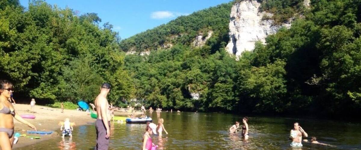 A group of people in a river surrounded by greenery and cliffs.