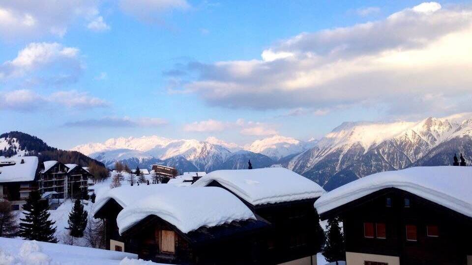 A snowy mountain village with wooden cabins and a backdrop of snow-covered peaks.