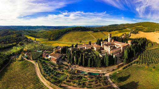 Badia a Passignano Italy aerial panorama in 12k high resolution. Chianti Classico wine region Tuscany. Medieval abbey and village surrounded by vineyards and cypresses. World Print quality scenery