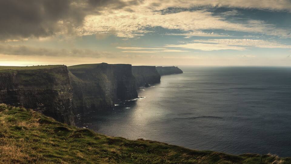 A coastal cliff landscape with a view of the sea.