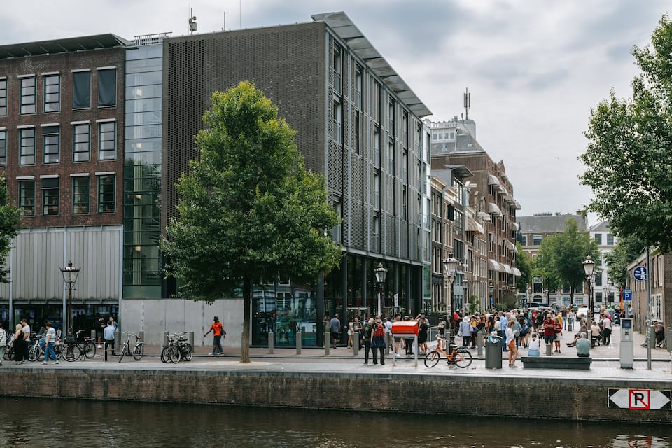 A riverside walkway with pedestrians, bicycles, and historic buildings.