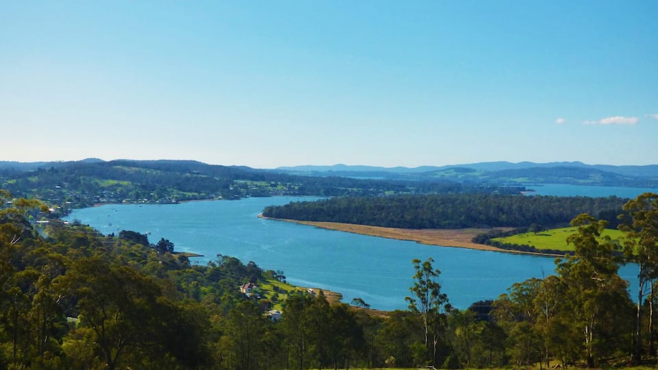 A river winding through a valley with vineyards and a lake in the distance.