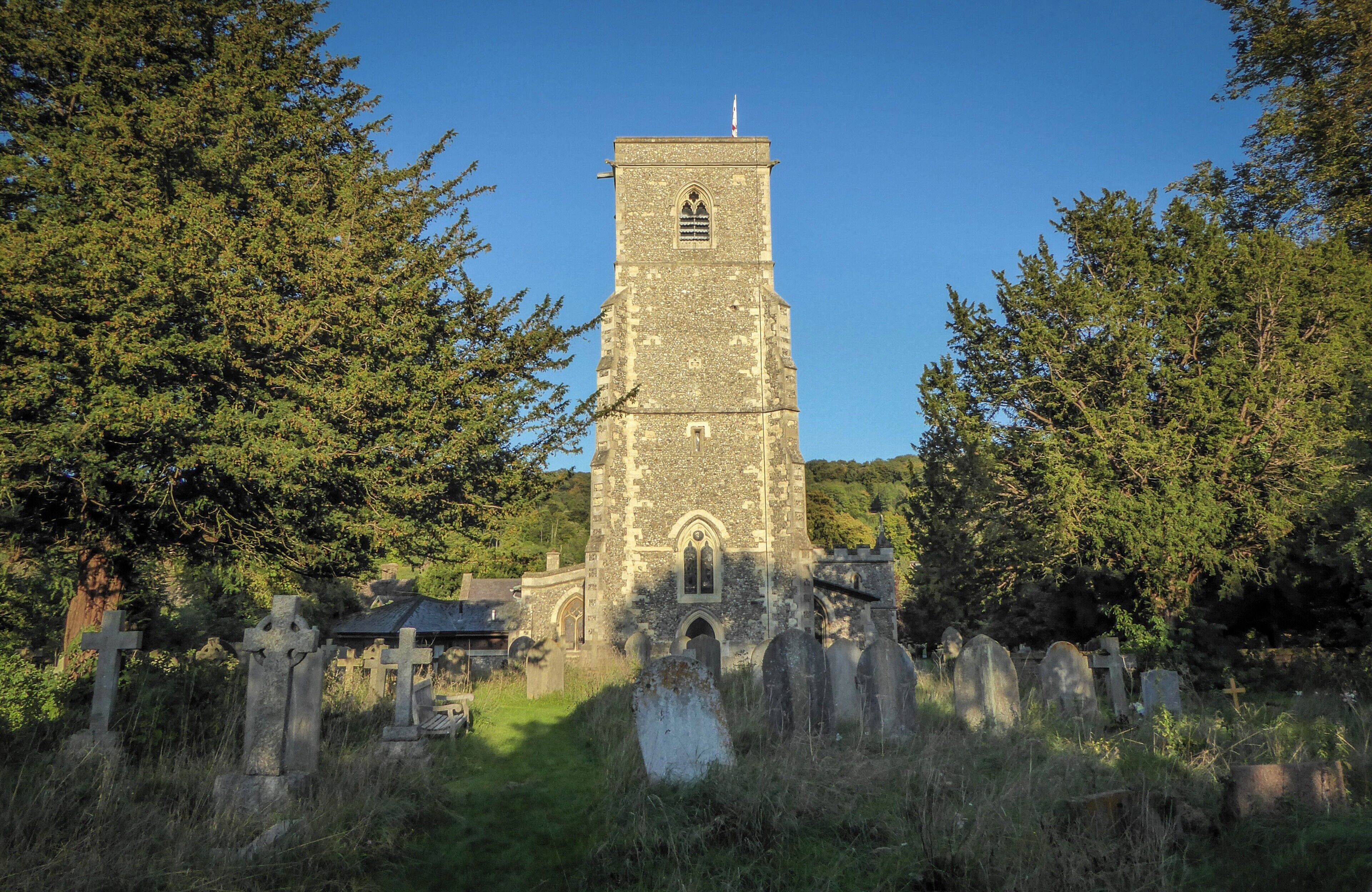 A stone church with a tall tower and crosses in a cemetery.
