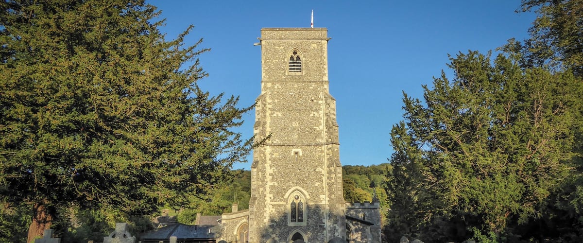 A stone church with a tall tower and crosses in a cemetery.