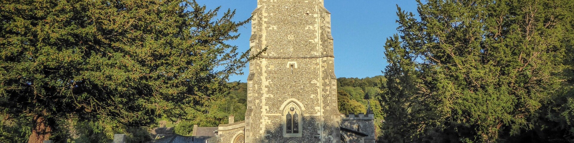 A stone church with a tall tower and crosses in a cemetery.
