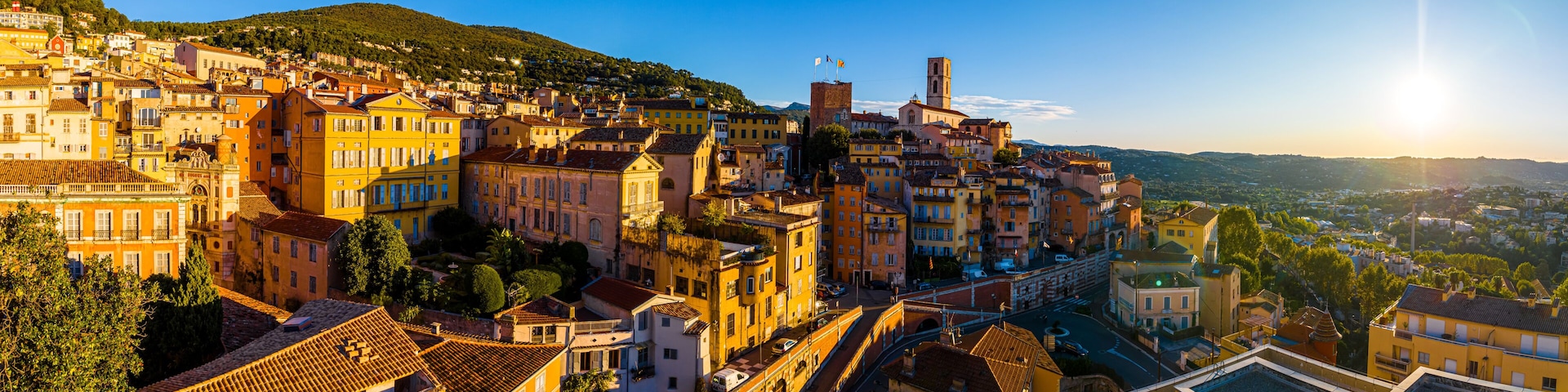 Un pueblo histórico con edificios de tejados de terracota, una iglesia destacada y una colina al fondo.