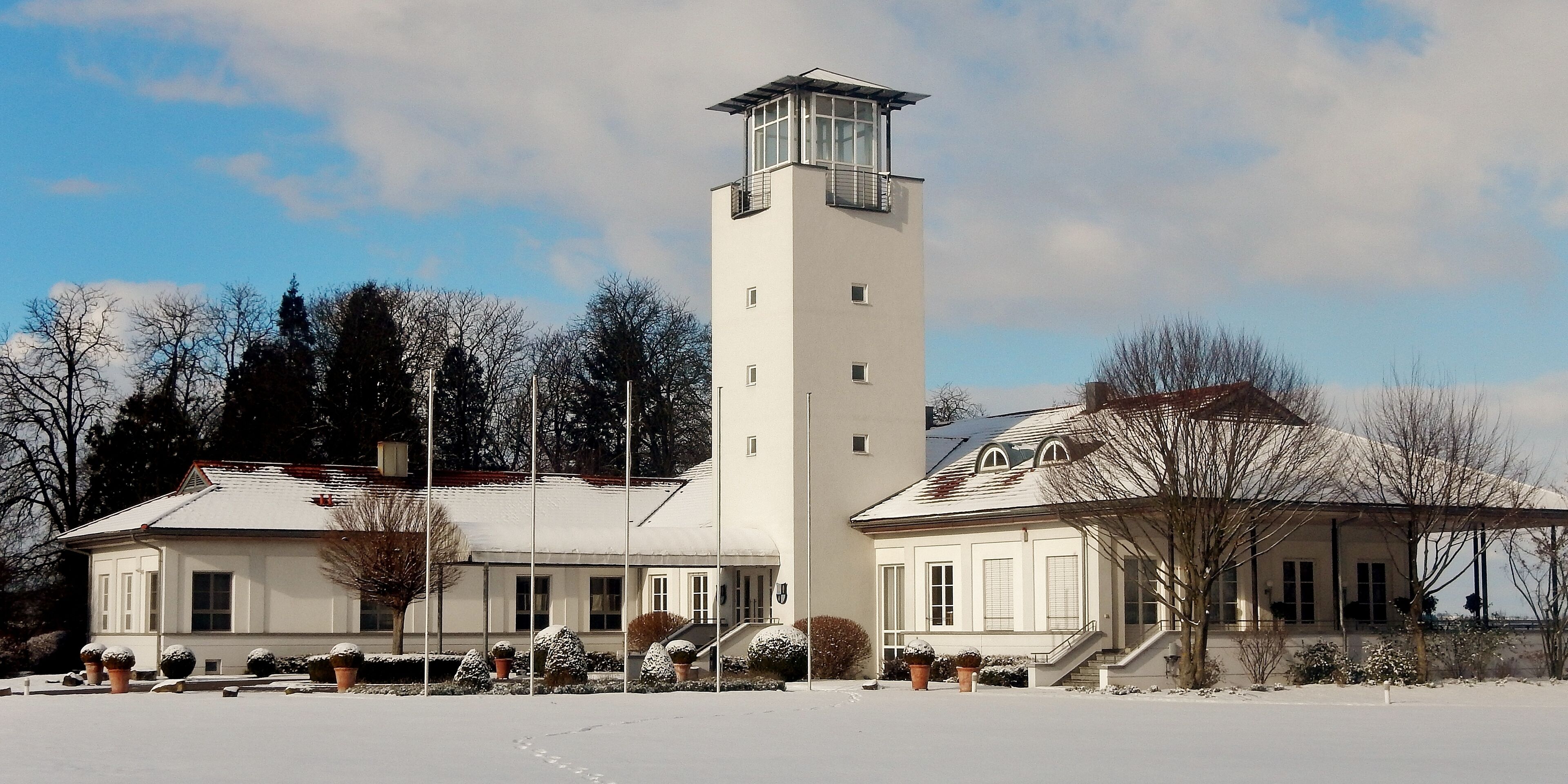 A large white building with a tall tower and a smaller attached building.