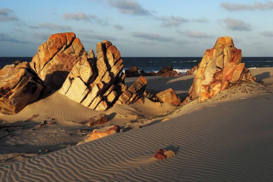 Et ørkenlandskab med markante klippeformationer og en sandstrand.