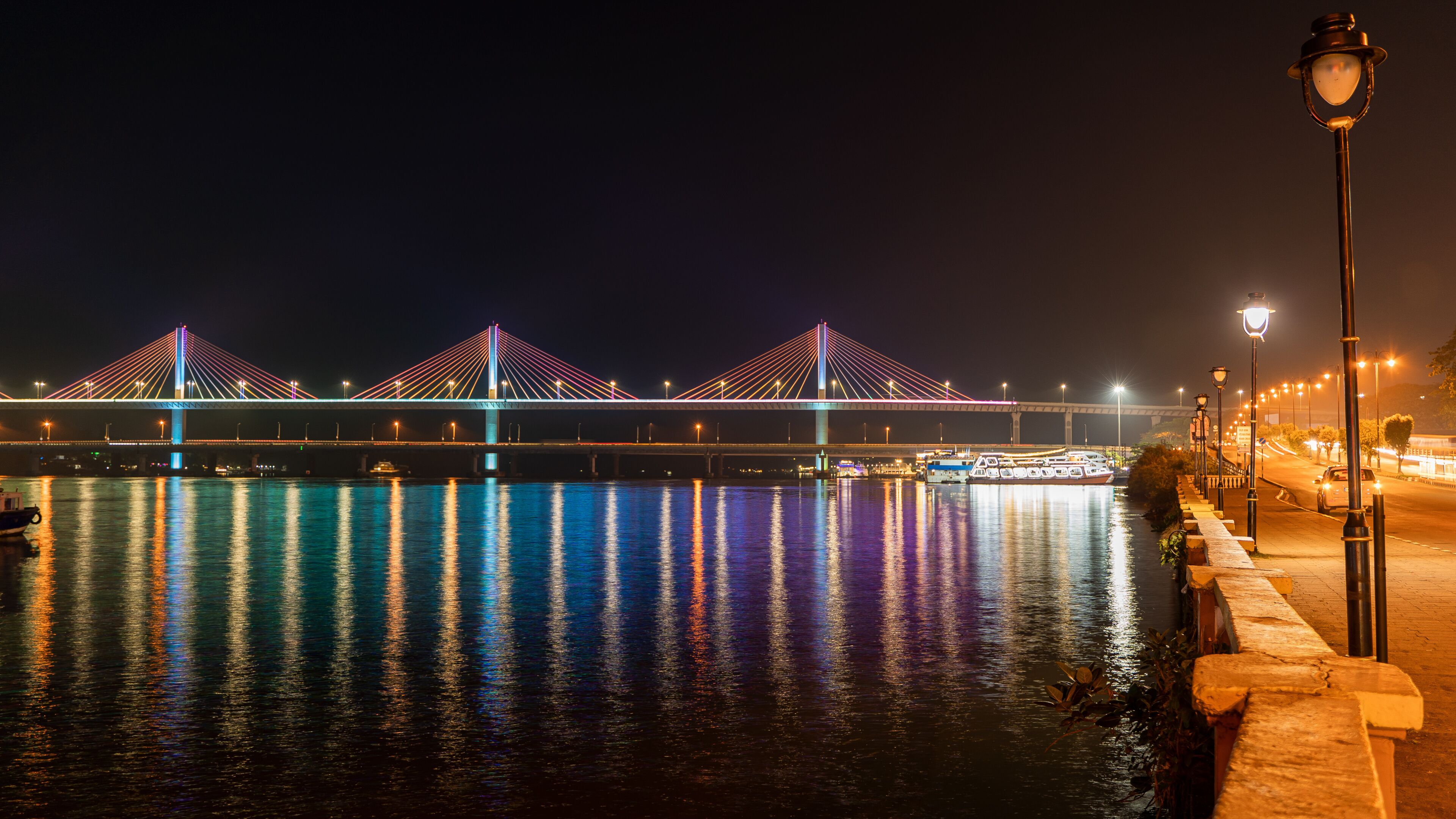 Beautiful view of the well illuminated Mandovi River Bridge in moonlight, with reflection of colored lights in river. Locally known as Atal Setu, this is one of the largest cable stayed bridge.