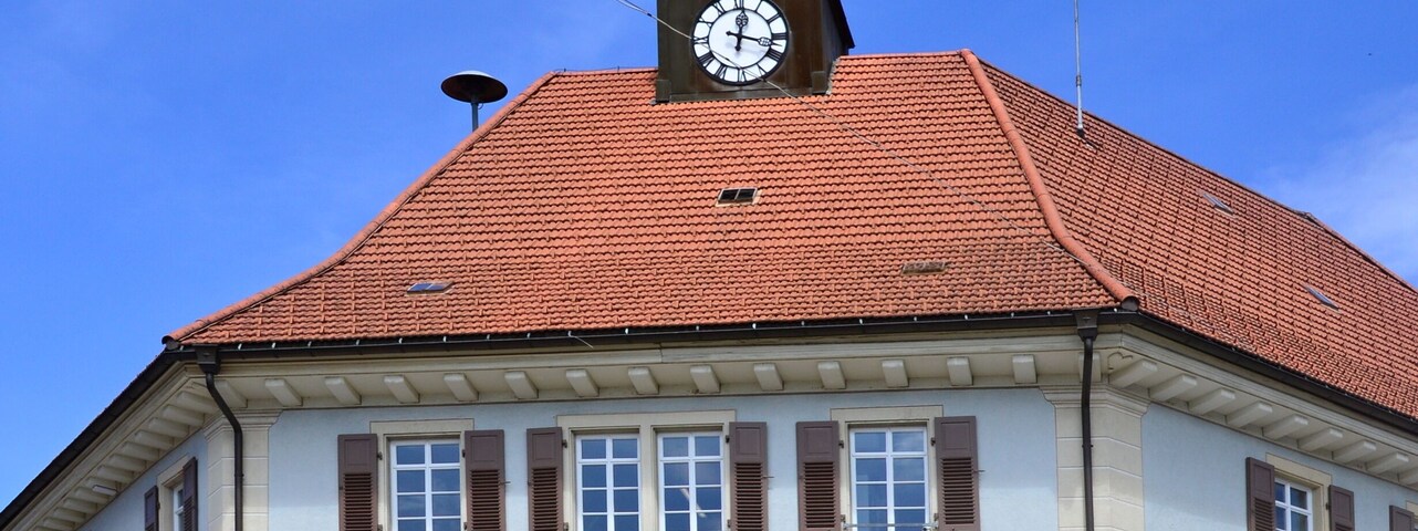 Um edifício com uma torre de relógio e uma placa com a inscrição 'RATHAUS'.