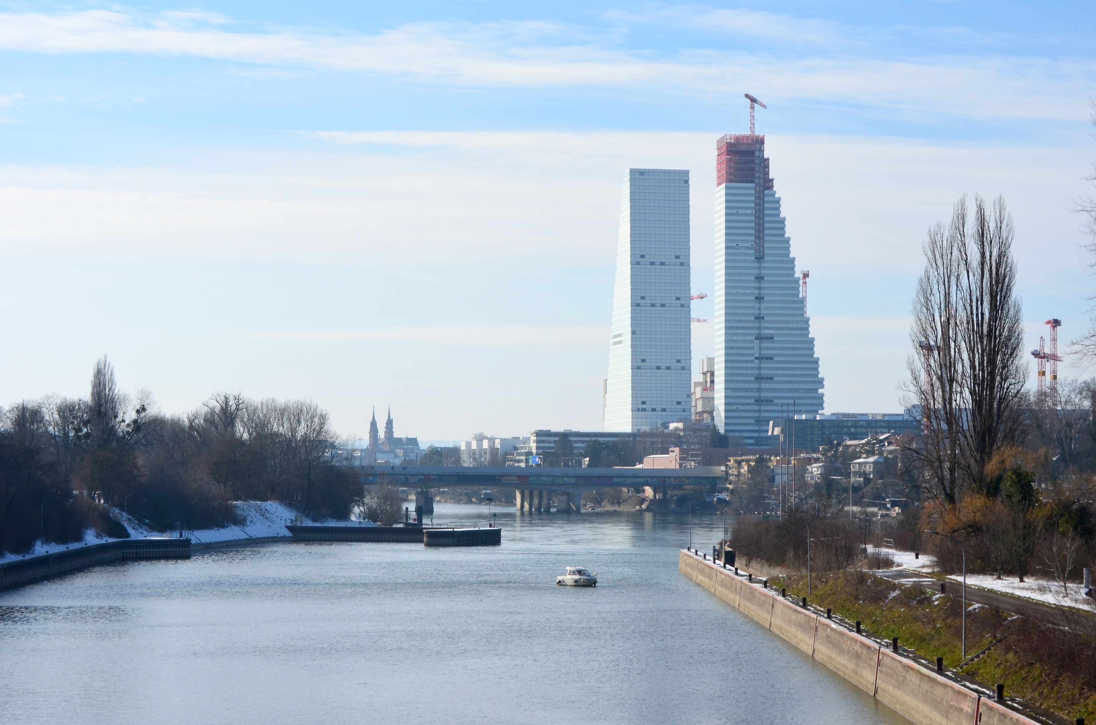 A river with a boat, a bridge, and modern buildings in the background.