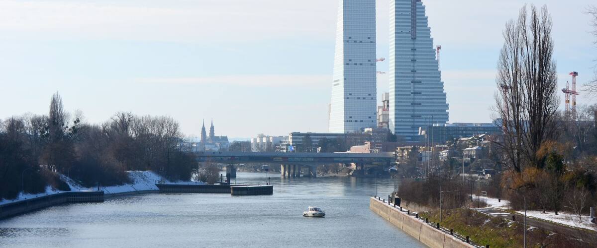 A river with a boat, a bridge, and modern buildings in the background.