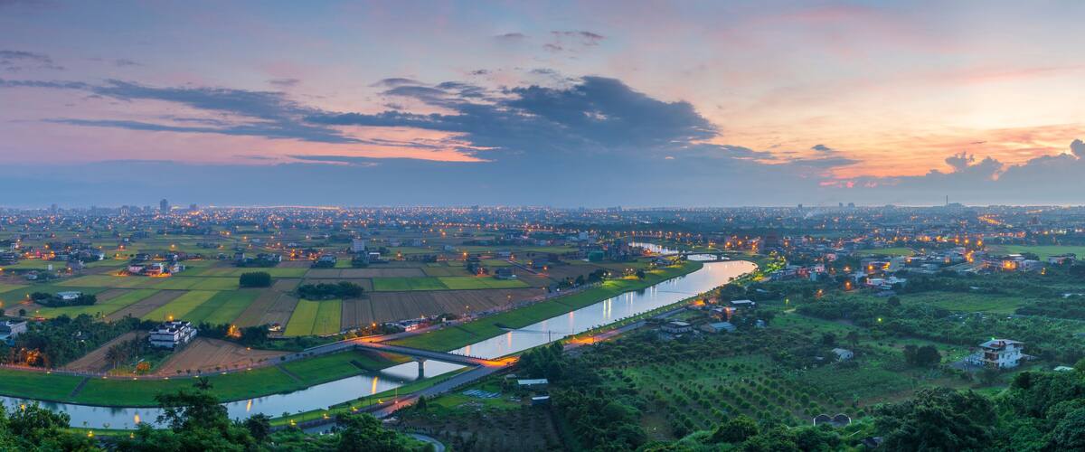 A panoramic view of a city at dusk with a river running through it.