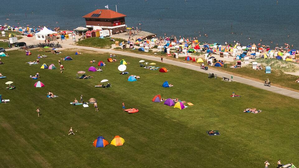 A crowded beach with numerous colorful tents and people enjoying the seaside.