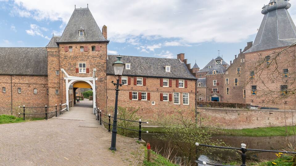A historic brick building with a tower and a canal in the foreground.