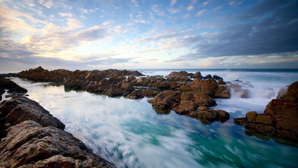 A rocky coastline with a calm sea and a cloudy sky.