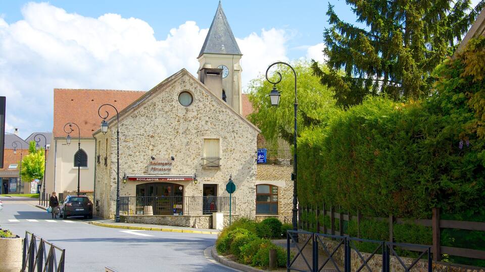 A stone building with a clock tower, a bakery, and a street with cars and pedestrians.