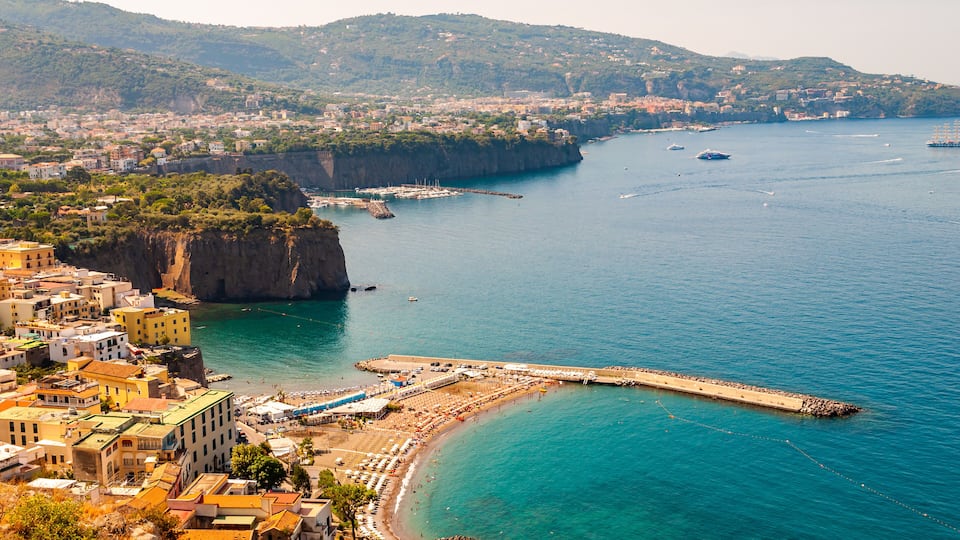A coastal town with a prominent cliff, a pier, and a beach.