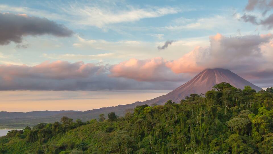 Arenal Volcano at Sunrise in Costa Rica, as the sun reflects on the newly formed clouds