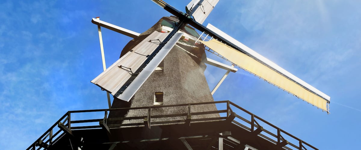 A windmill against a clear blue sky with the sun shining brightly.