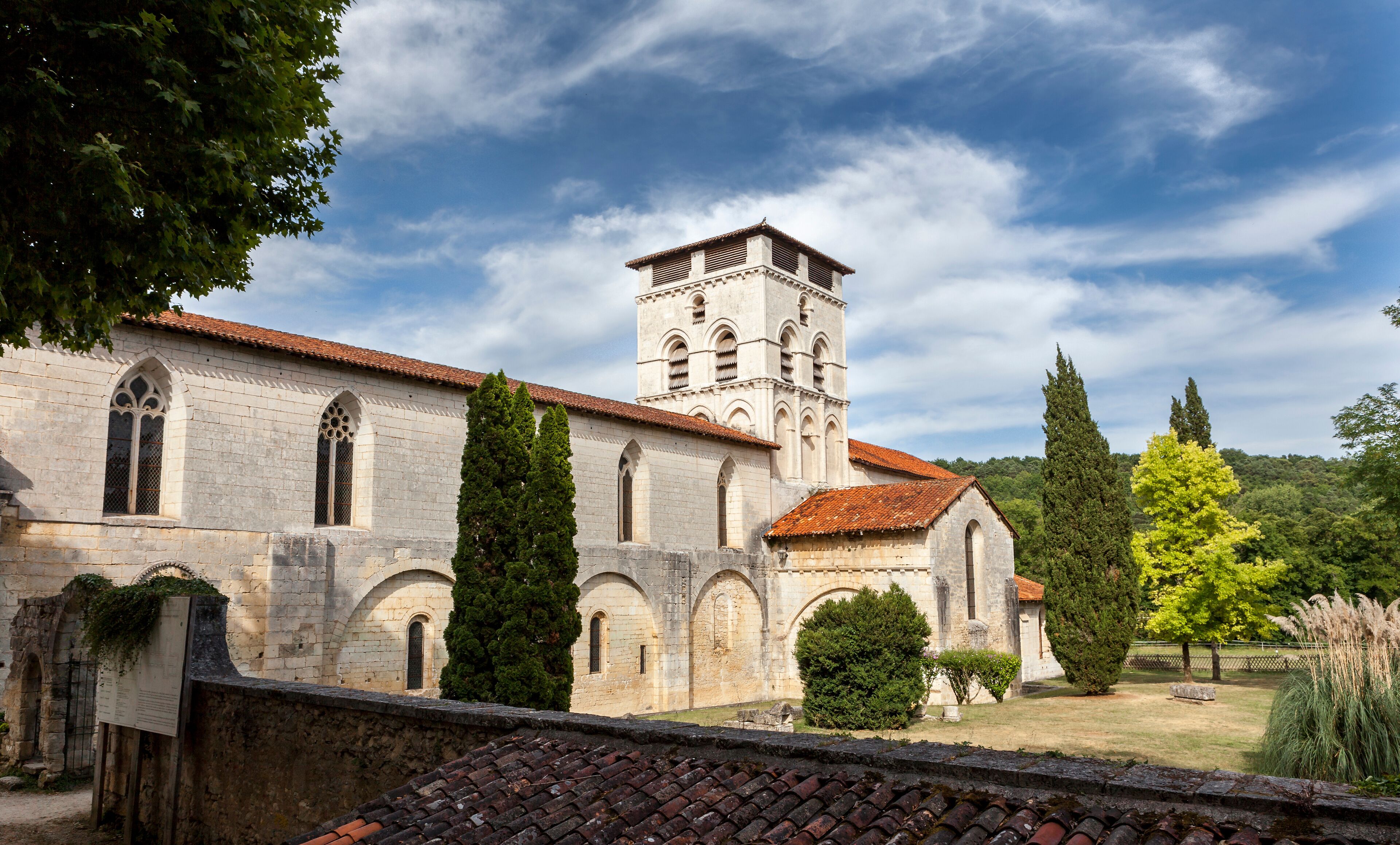 A historic church with a bell tower, surrounded by trees and a clear sky.